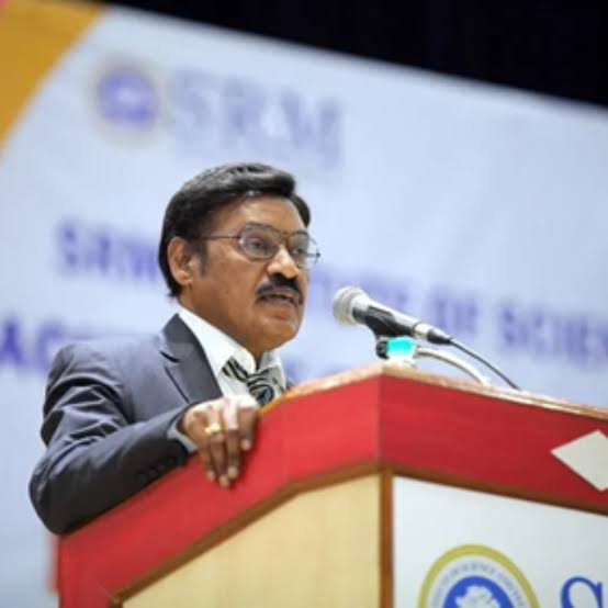 Dr. T. R. Paarivendhar speaking at a red lectern in front of an SRM Institute of Science and Technology banner