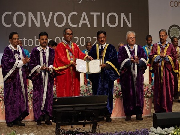 Dr. T. R. Paarivendhar in red academic robes holding an open certificate on a convocation stage with other robed dignitaries, under a banner dated October 08, 2022