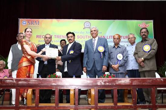 Dr. T. R. Paarivendhar presenting a memento on stage with guests, beneath a banner reading Recent Trends in South Indian Literature